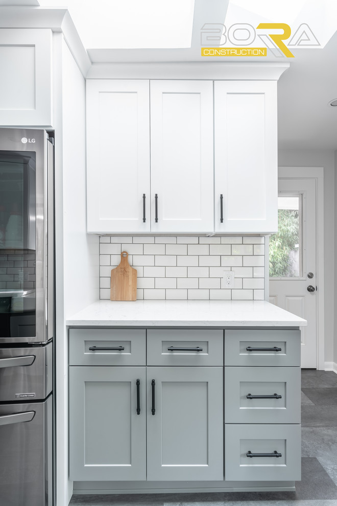 This is an example of a medium sized traditional galley kitchen/diner in Seattle with a belfast sink, shaker cabinets, yellow cabinets, engineered stone countertops, white splashback, ceramic splashback, stainless steel appliances, vinyl flooring, no island and grey floors.