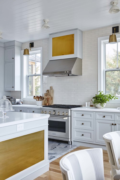 Brass and Gray Harmony: Light Gray Kitchen Cabinets with White Subway Tiles and Brass Knobs