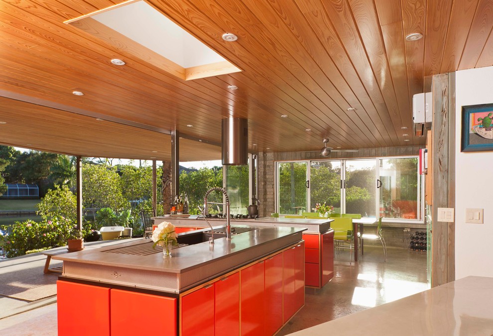 Пример оригинального дизайна: кухня в стиле ретро с обеденным столом, врезной мойкой, столешницей из бетона, техникой из нержавеющей стали, плоскими фасадами и красными фасадами