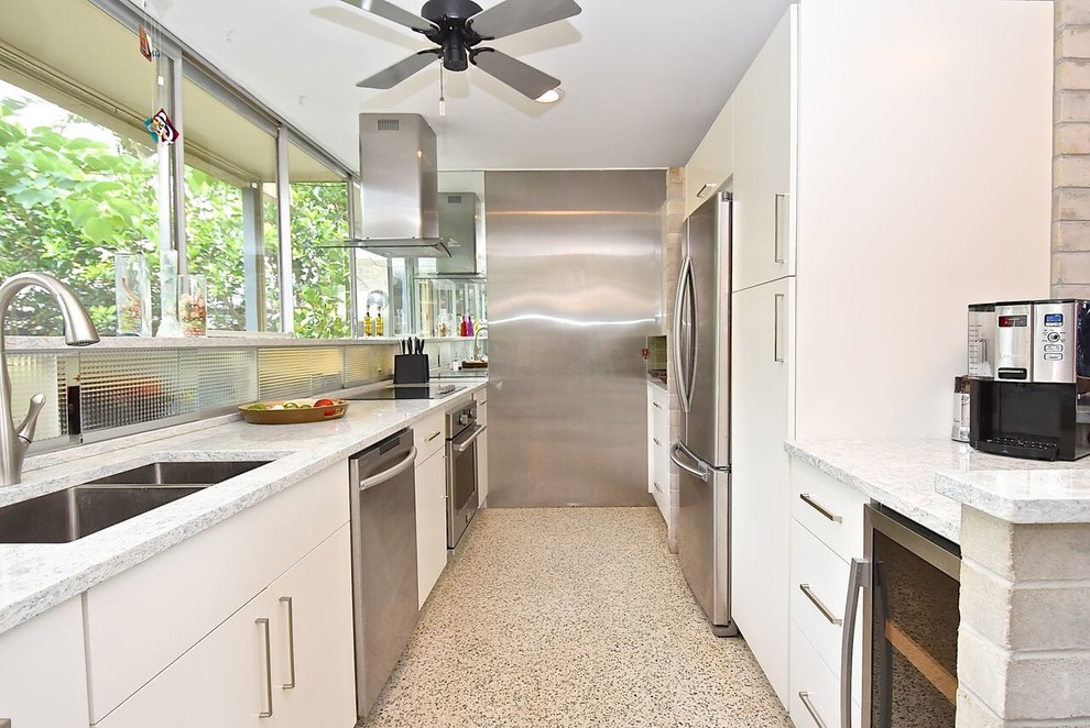 Large mid-century modern galley terrazzo floor and white floor open concept kitchen photo in Other with an integrated sink, flat-panel cabinets, white cabinets, quartz countertops, gray backsplash, stainless steel appliances, an island and white countertops