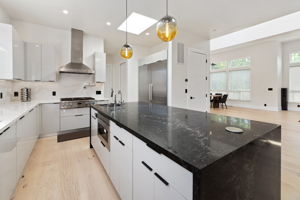 Immagine di un cucina con isola centrale minimalista con top in quarzite, paraspruzzi bianco, parquet chiaro e top nero