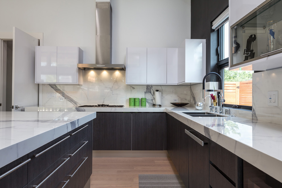 Mid-sized trendy l-shaped light wood floor and beige floor eat-in kitchen photo in San Francisco with a double-bowl sink, flat-panel cabinets, black cabinets, solid surface countertops, white backsplash, marble backsplash, stainless steel appliances, an island and white countertops