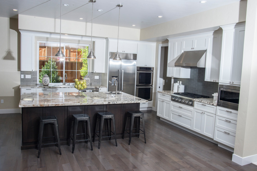Example of a large transitional l-shaped dark wood floor and brown floor eat-in kitchen design in San Francisco with an undermount sink, shaker cabinets, white cabinets, granite countertops, gray backsplash, subway tile backsplash, stainless steel appliances and an island