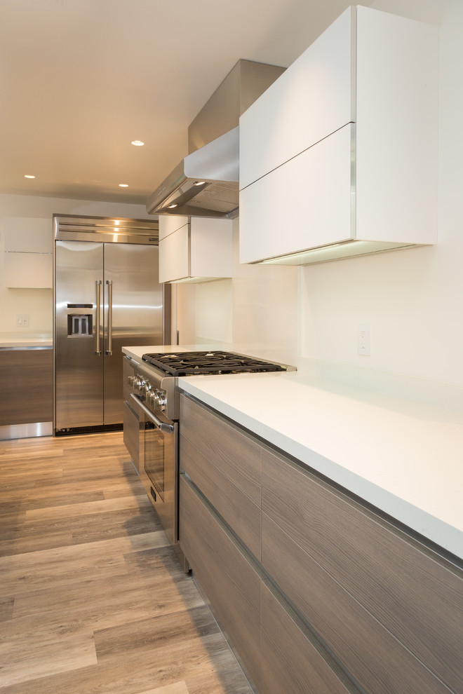 Example of a mid-sized minimalist l-shaped laminate floor and beige floor eat-in kitchen design in San Francisco with an undermount sink, flat-panel cabinets, light wood cabinets, quartz countertops, white backsplash, glass tile backsplash, stainless steel appliances and an island