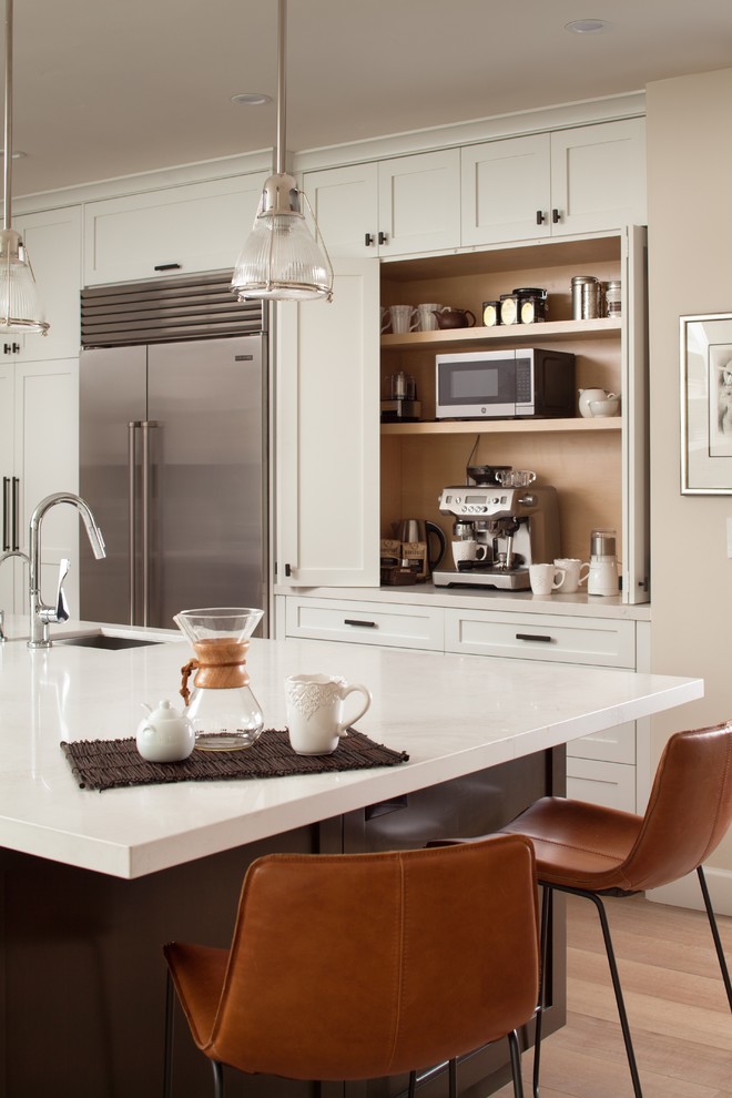 This is an example of a large modern l-shaped kitchen/diner in San Francisco with a submerged sink, shaker cabinets, white cabinets, engineered stone countertops, grey splashback, cement tile splashback, stainless steel appliances, light hardwood flooring, an island, beige floors and white worktops.