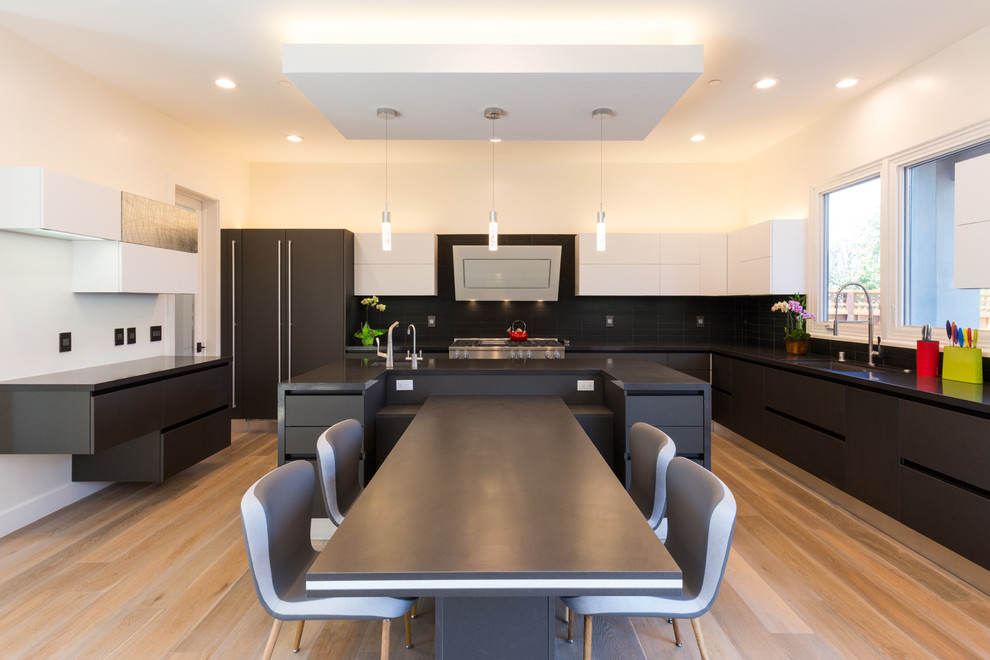 Bild på ett stort funkis svart svart kök och matrum, med en undermonterad diskho, släta luckor, bänkskiva i kvarts, svart stänkskydd, stänkskydd i keramik, rostfria vitvaror, en köksö, ljust trägolv och beiget golv
