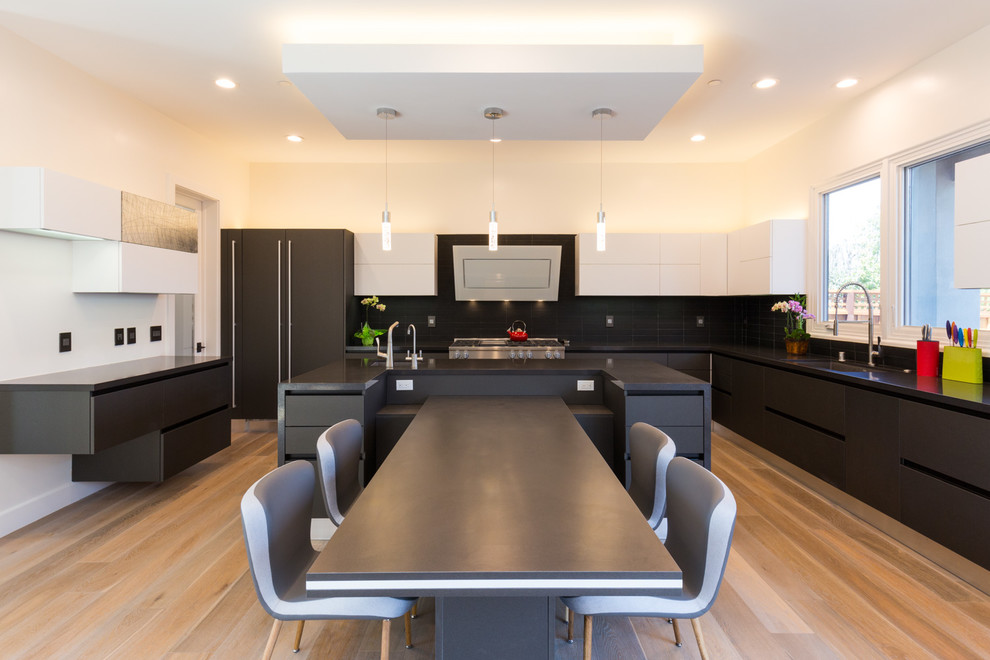 Foto de cocina comedor minimalista grande con fregadero bajoencimera, armarios con paneles lisos, encimera de cuarzo compacto, salpicadero negro, salpicadero de azulejos de cerámica, electrodomésticos de acero inoxidable, una isla, encimeras negras, suelo de madera clara, suelo beige, con blanco y negro y barras de cocina