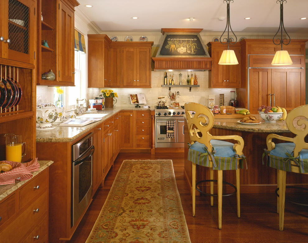 Bild på ett vintage kök, med en undermonterad diskho, rostfria vitvaror, en köksö, mellanmörkt trägolv, luckor med profilerade fronter, skåp i mellenmörkt trä, granitbänkskiva, vitt stänkskydd och stänkskydd i keramik