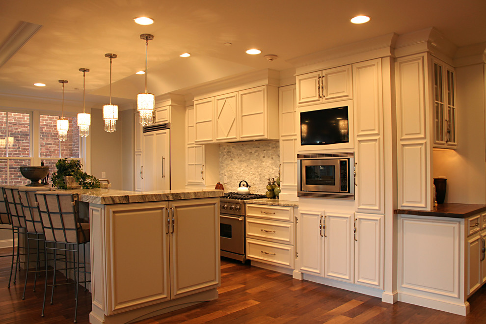 Bild på ett stort funkis linjärt kök med öppen planlösning, med luckor med upphöjd panel, vita skåp, granitbänkskiva, rostfria vitvaror, mellanmörkt trägolv och en köksö