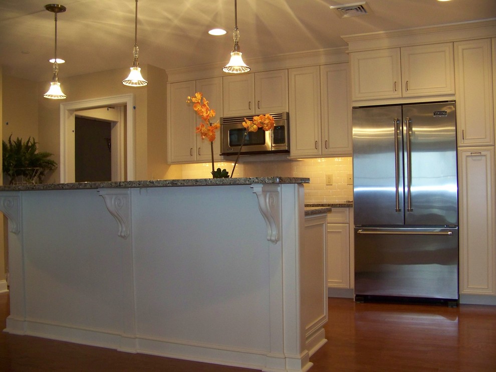 Offene, Einzeilige, Mittelgroße Moderne Küche mit profilierten Schrankfronten, weißen Schränken, Granit-Arbeitsplatte, Küchengeräten aus Edelstahl, braunem Holzboden und Kücheninsel in Boston