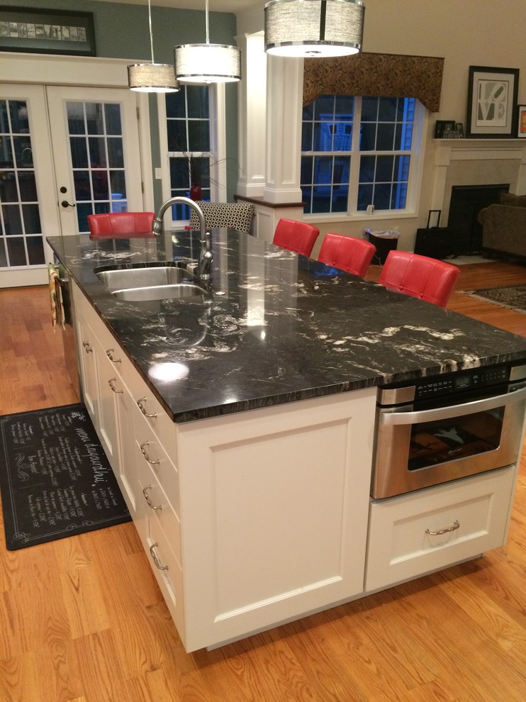 Moderne Küche mit Doppelwaschbecken, Schrankfronten mit vertiefter Füllung, weißen Schränken, Granit-Arbeitsplatte, Küchenrückwand in Blau, Rückwand aus Keramikfliesen, Küchengeräten aus Edelstahl, hellem Holzboden und Kücheninsel in Boston