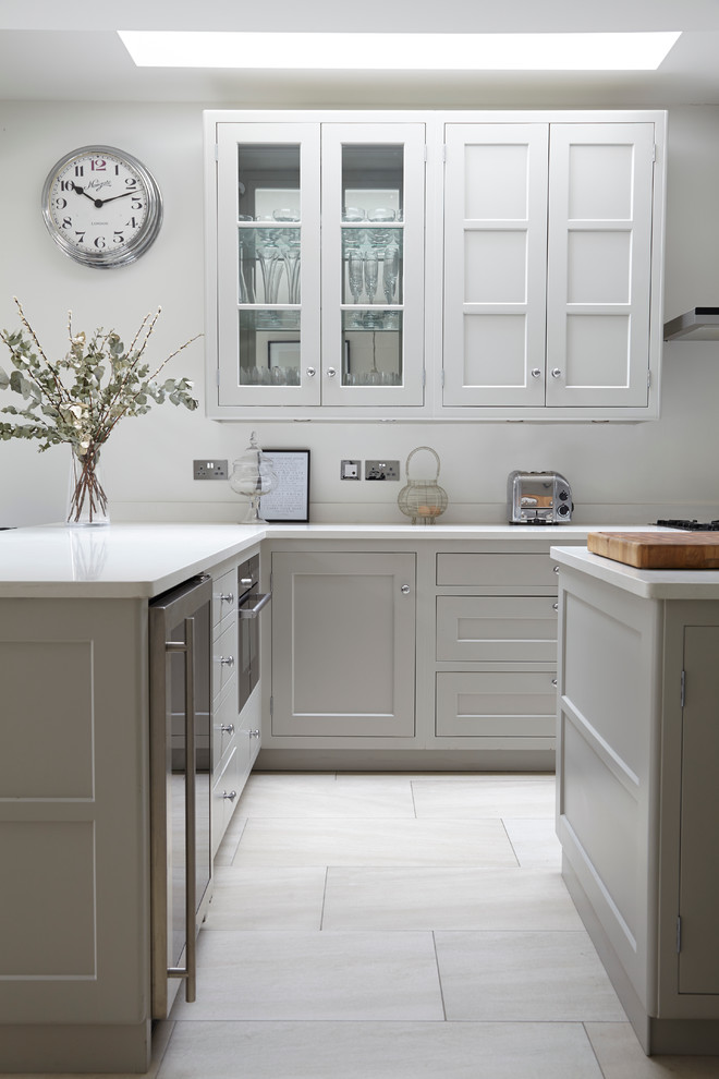 Modelo de cocina gris y blanca clásica renovada con armarios estilo shaker, puertas de armario blancas y una isla