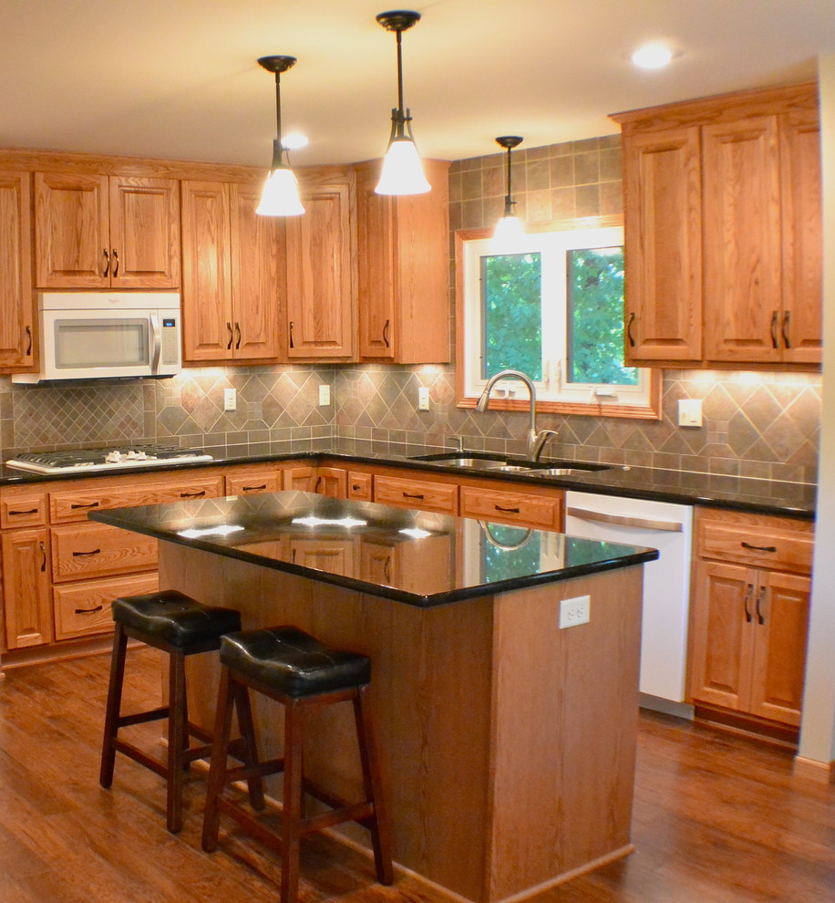 Example of a classic u-shaped eat-in kitchen design in Minneapolis with an undermount sink, raised-panel cabinets, medium tone wood cabinets, granite countertops, multicolored backsplash, ceramic backsplash and white appliances