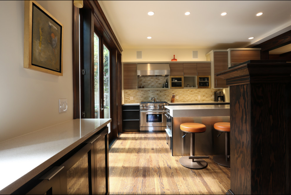 Photo of a large bohemian galley kitchen/diner in Portland with a submerged sink, flat-panel cabinets, light wood cabinets, engineered stone countertops, yellow splashback, glass tiled splashback, stainless steel appliances, dark hardwood flooring and an island.