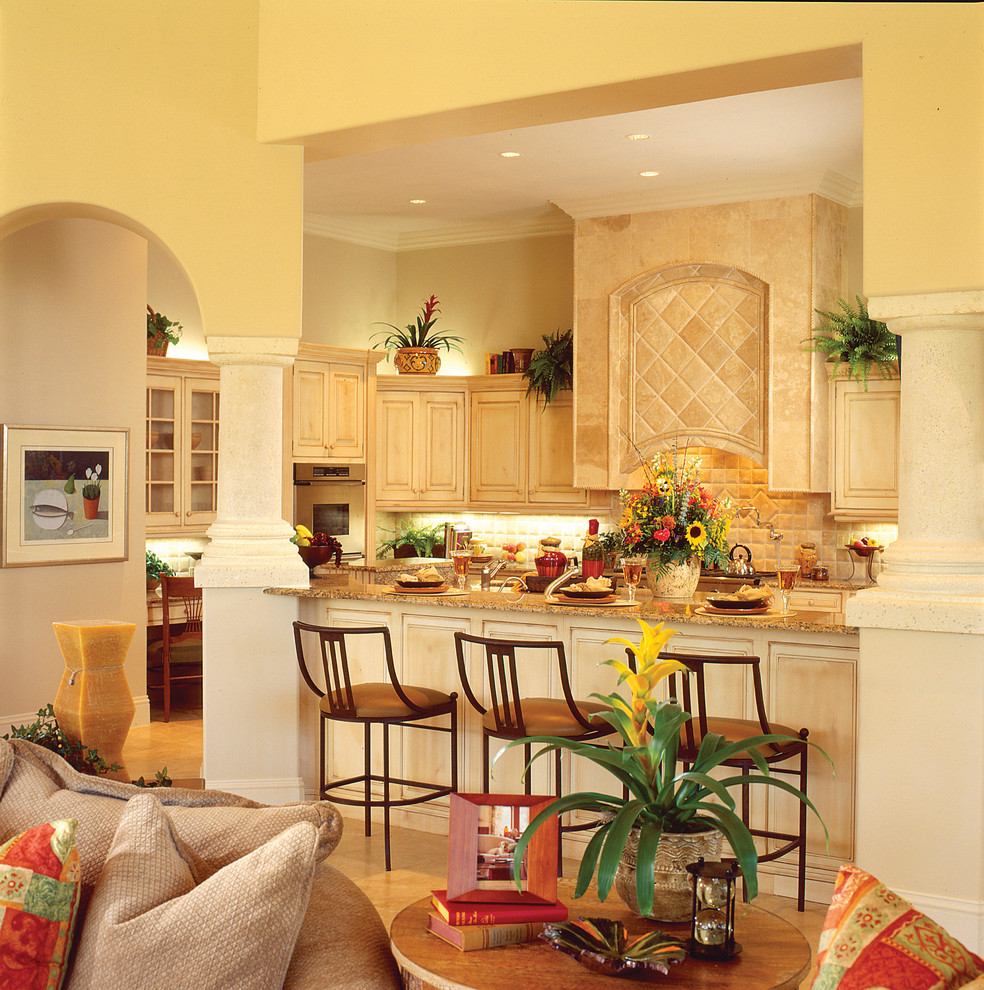 Bild på ett stort medelhavsstil kök, med en undermonterad diskho, luckor med upphöjd panel, skåp i slitet trä, granitbänkskiva, beige stänkskydd, stänkskydd i stenkakel, integrerade vitvaror, travertin golv och en köksö