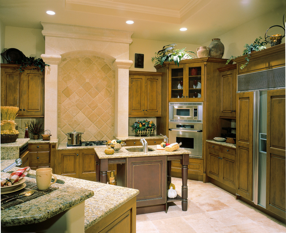 Bild på ett stort medelhavsstil kök, med en undermonterad diskho, luckor med upphöjd panel, skåp i mörkt trä, granitbänkskiva, beige stänkskydd, stänkskydd i stenkakel, integrerade vitvaror, travertin golv och en köksö