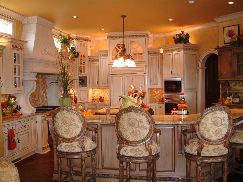 Foto på ett stort medelhavsstil kök, med en undermonterad diskho, luckor med upphöjd panel, skåp i slitet trä, granitbänkskiva, beige stänkskydd, stänkskydd i keramik, integrerade vitvaror, mörkt trägolv och en köksö
