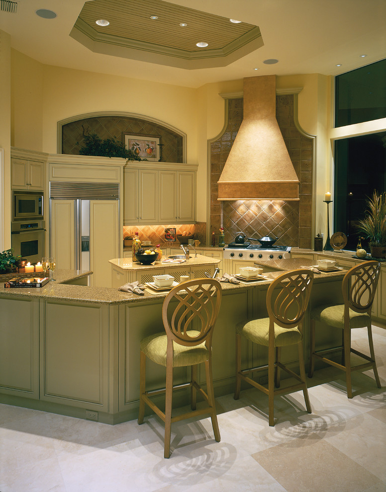 Exempel på ett stort medelhavsstil kök, med en undermonterad diskho, luckor med upphöjd panel, gröna skåp, granitbänkskiva, beige stänkskydd, stänkskydd i stenkakel, integrerade vitvaror, travertin golv och en köksö