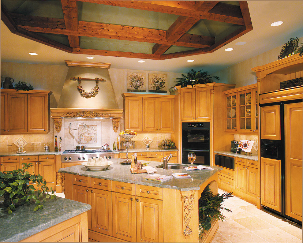 Foto på ett stort medelhavsstil kök, med en undermonterad diskho, luckor med upphöjd panel, skåp i mellenmörkt trä, granitbänkskiva, beige stänkskydd, stänkskydd i stenkakel, svarta vitvaror, travertin golv och en köksö