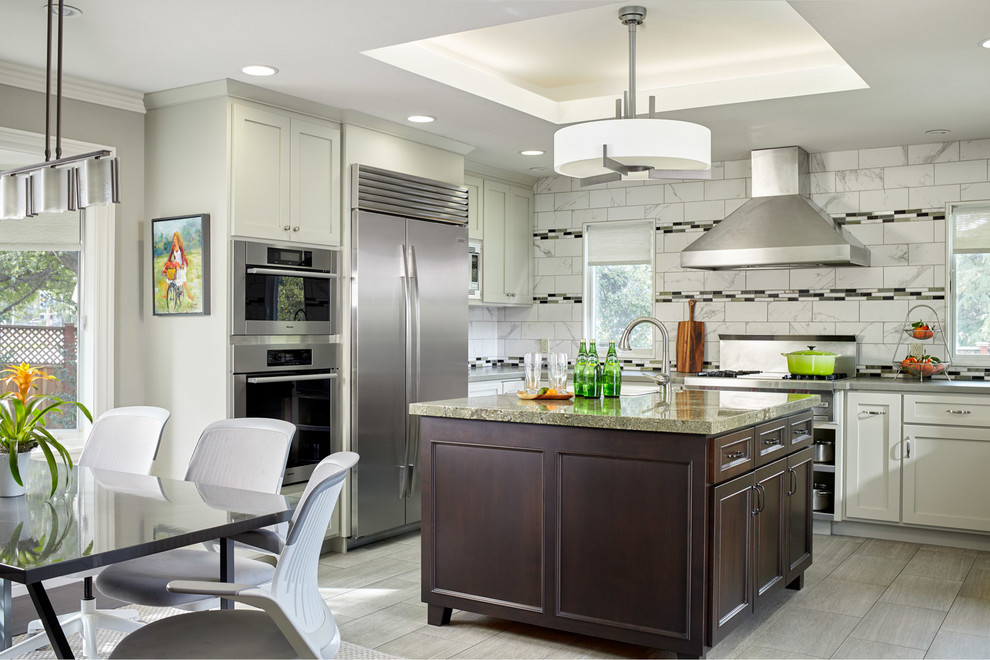 Inspiration for a transitional u-shaped gray floor kitchen remodel in San Francisco with shaker cabinets, white cabinets, white backsplash, stainless steel appliances, an island and gray countertops
