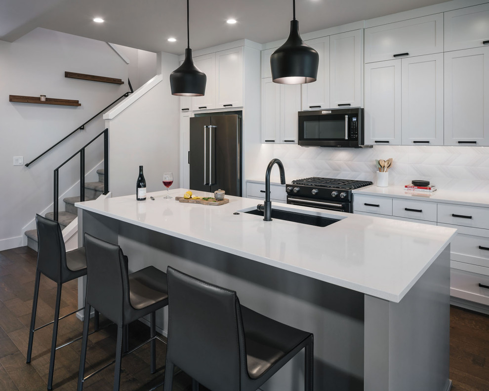 Eat-in kitchen - mid-sized transitional single-wall dark wood floor and brown floor eat-in kitchen idea in Other with an undermount sink, shaker cabinets, white cabinets, quartzite countertops, white backsplash, ceramic backsplash, black appliances, an island and white countertops