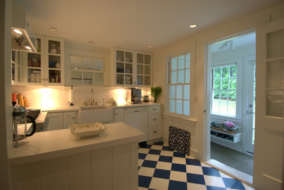 Enclosed kitchen - mid-sized traditional u-shaped porcelain tile enclosed kitchen idea in Providence with a farmhouse sink, glass-front cabinets, white cabinets, quartz countertops, white backsplash, white appliances and a peninsula