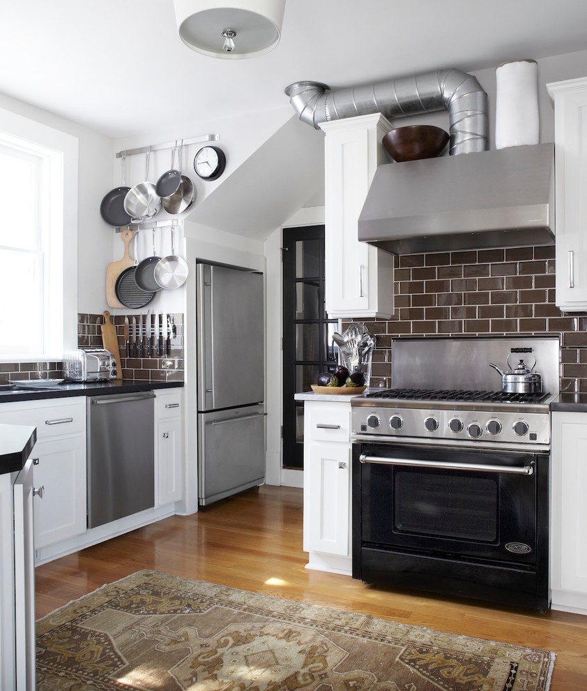 Example of a classic u-shaped eat-in kitchen design in San Francisco with an undermount sink, shaker cabinets, white cabinets, granite countertops, brown backsplash, subway tile backsplash and black appliances