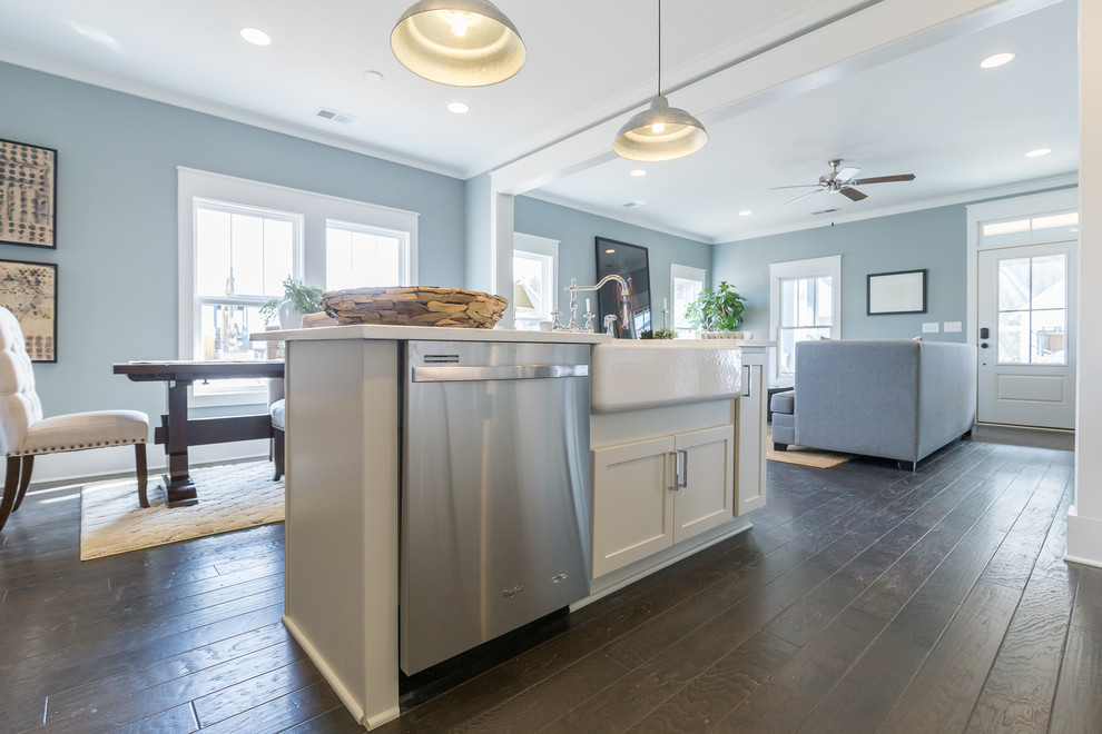 Example of a mid-sized transitional single-wall dark wood floor and brown floor open concept kitchen design in Birmingham with a farmhouse sink, shaker cabinets, white cabinets, quartz countertops, white backsplash, subway tile backsplash, stainless steel appliances and an island