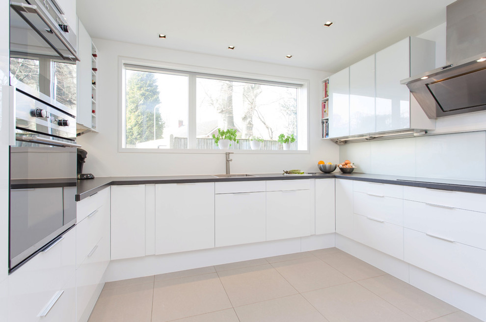 Moderne Küche in U-Form mit flächenbündigen Schrankfronten, weißen Schränken und Küchengeräten aus Edelstahl in Hampshire