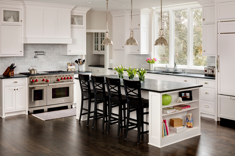 Traditional kitchen in Milwaukee with a submerged sink, shaker cabinets, white cabinets, grey splashback, stainless steel appliances, dark hardwood flooring and an island.