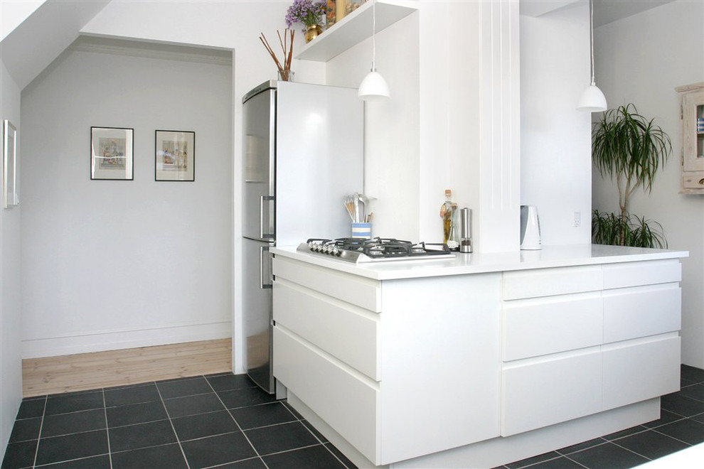 Foto di una cucina minimal di medie dimensioni con lavello sottopiano, ante bianche, top in superficie solida, elettrodomestici in acciaio inossidabile e pavimento in ardesia