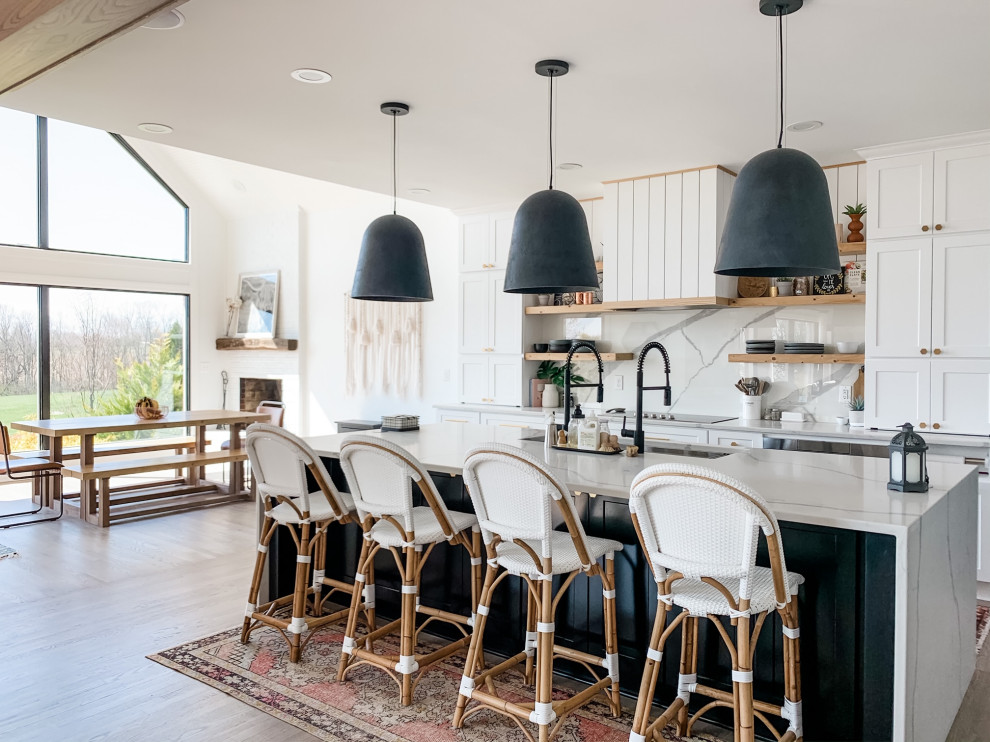 Inspiration for a large scandinavian l-shaped kitchen/diner in Louisville with a single-bowl sink, shaker cabinets, white cabinets, engineered stone countertops, white splashback, engineered quartz splashback, stainless steel appliances, light hardwood flooring, an island, brown floors and white worktops.