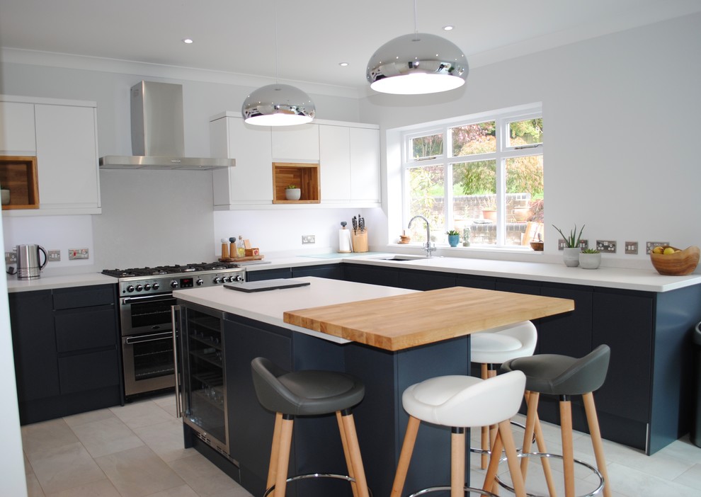 This is an example of a medium sized scandi u-shaped enclosed kitchen in Hertfordshire with a built-in sink, flat-panel cabinets, stainless steel appliances, an island, grey floors and white worktops.
