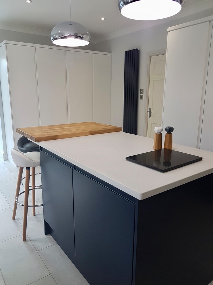 Mid-sized danish u-shaped gray floor enclosed kitchen photo in Hertfordshire with a drop-in sink, flat-panel cabinets, stainless steel appliances, an island and white countertops