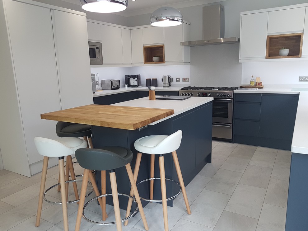 Photo of a medium sized scandi u-shaped enclosed kitchen in Hertfordshire with a built-in sink, flat-panel cabinets, stainless steel appliances, an island, grey floors and white worktops.