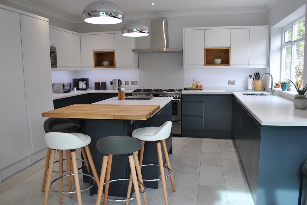 Geschlossene, Mittelgroße Moderne Küche in U-Form mit Einbauwaschbecken, flächenbündigen Schrankfronten, Küchengeräten aus Edelstahl, Kücheninsel, grauem Boden und weißer Arbeitsplatte in Hertfordshire