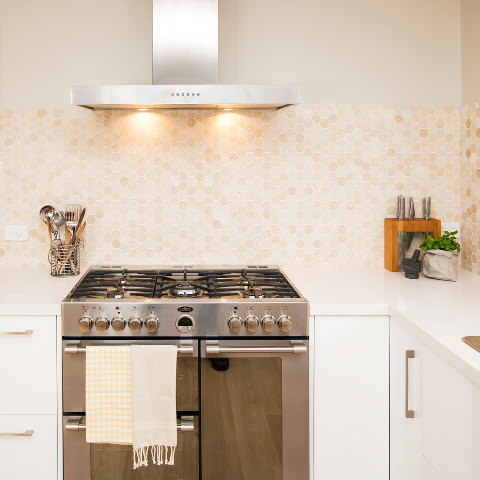 Moderne Wohnküche mit flächenbündigen Schrankfronten, weißen Schränken, Quarzwerkstein-Arbeitsplatte, Küchenrückwand in Beige, Rückwand aus Keramikfliesen, hellem Holzboden und Kücheninsel in Toronto