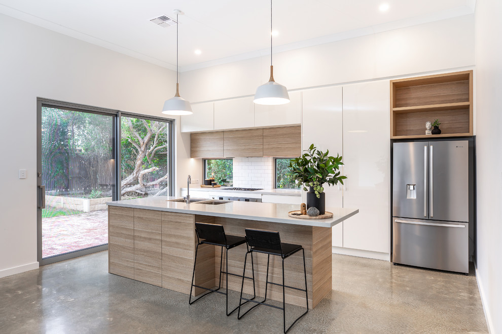 Medium sized contemporary galley kitchen pantry in Adelaide with a submerged sink, flat-panel cabinets, light wood cabinets, engineered stone countertops, white splashback, metro tiled splashback, stainless steel appliances, concrete flooring, an island, grey floors and grey worktops.