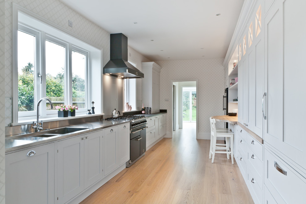 Scandi kitchen in London with shaker cabinets, white cabinets, wood worktops and light hardwood flooring.