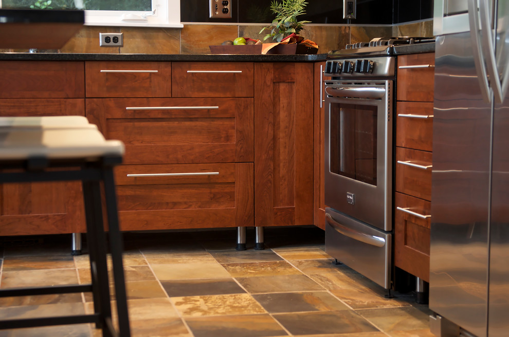 Kleine Moderne Wohnküche in L-Form mit Schrankfronten im Shaker-Stil, hellbraunen Holzschränken, Granit-Arbeitsplatte, Küchengeräten aus Edelstahl und Schieferboden in Sonstige