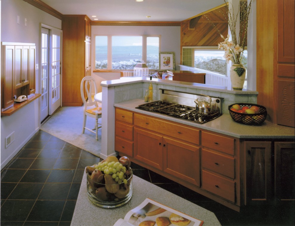Example of a large trendy u-shaped slate floor eat-in kitchen design in San Francisco with an undermount sink, shaker cabinets, medium tone wood cabinets, solid surface countertops, green backsplash, ceramic backsplash, black appliances and an island