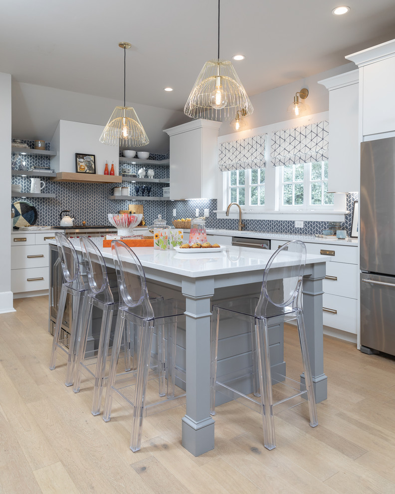 Bild på ett skandinaviskt vit vitt l-kök, med en undermonterad diskho, släta luckor, vita skåp, grått stänkskydd, rostfria vitvaror, ljust trägolv, en köksö och beiget golv