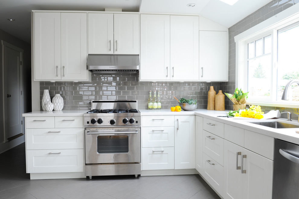 Small 1960s l-shaped porcelain tile eat-in kitchen photo in Vancouver with an undermount sink, shaker cabinets, white cabinets, solid surface countertops, gray backsplash, glass tile backsplash, stainless steel appliances and no island