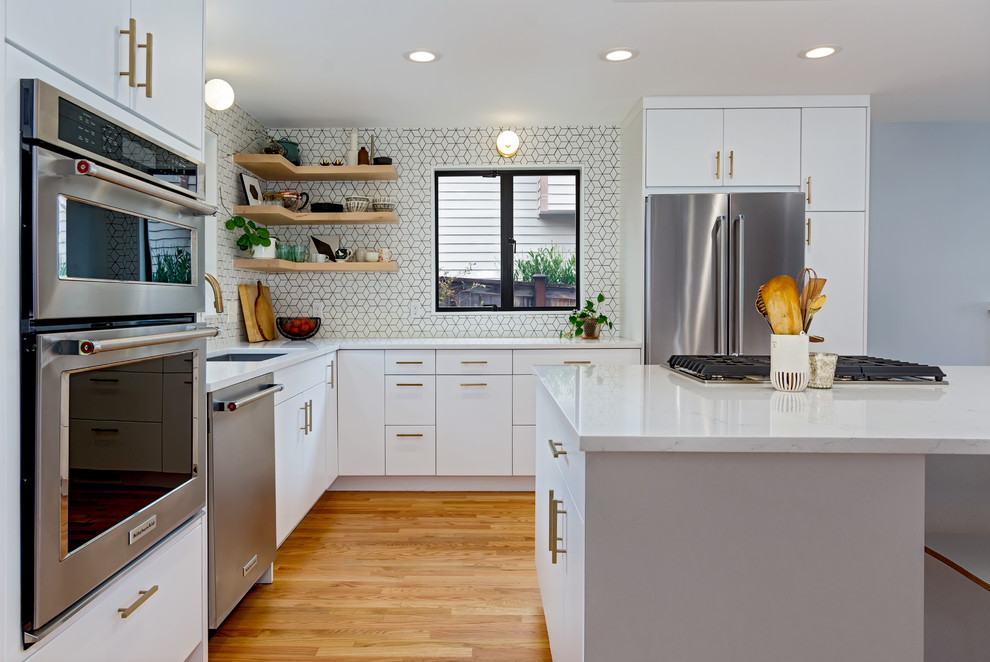 Small scandi l-shaped kitchen/diner in Seattle with a submerged sink, flat-panel cabinets, white cabinets, engineered stone countertops, white splashback, mosaic tiled splashback, stainless steel appliances, medium hardwood flooring, an island, brown floors and white worktops.