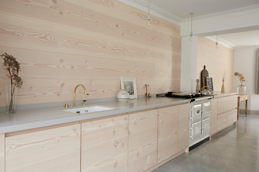 Example of a huge danish galley concrete floor open concept kitchen design in London with light wood cabinets and an island