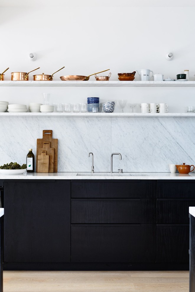 Idéer för att renovera ett avskilt, mellanstort nordiskt linjärt kök, med en undermonterad diskho, släta luckor, svarta skåp, marmorbänkskiva, vitt stänkskydd, stänkskydd i sten och ljust trägolv