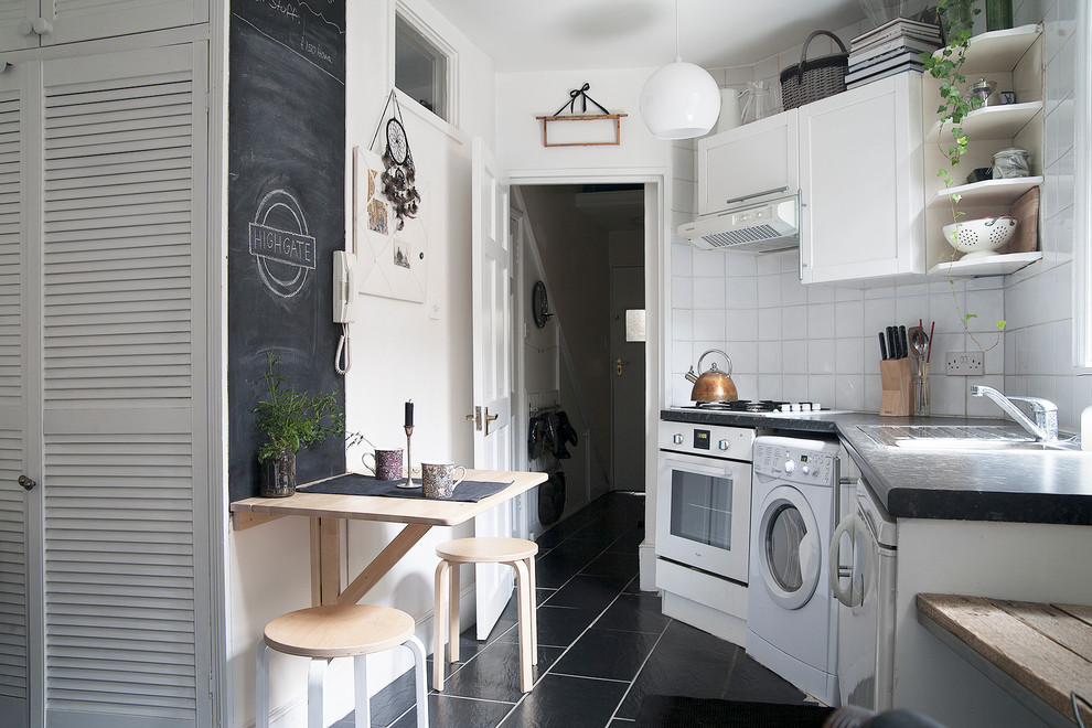 Example of a small danish single-wall black floor kitchen design in London with shaker cabinets, white cabinets, white backsplash, ceramic backsplash and white appliances