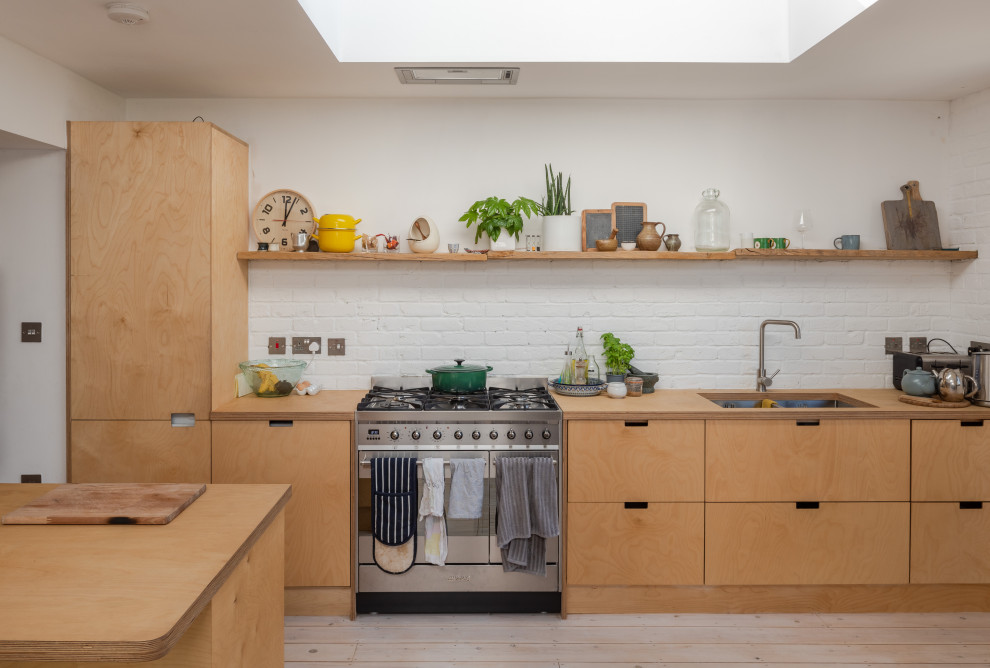 Inspiration for a scandinavian galley light wood floor and beige floor kitchen remodel in London with flat-panel cabinets, light wood cabinets, wood countertops, an island, an undermount sink, white backsplash, brick backsplash, stainless steel appliances and beige countertops