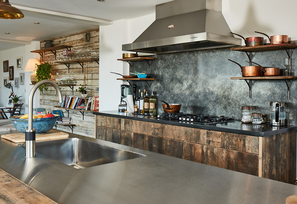 Exemple d'une cuisine parallèle scandinave en bois foncé avec un évier intégré, un placard à porte plane, un plan de travail en inox, une crédence métallisée, une crédence en dalle métallique, îlot et un plan de travail gris.