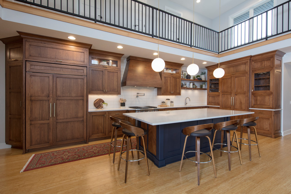 Kitchen - large transitional l-shaped medium tone wood floor and brown floor kitchen idea in Cleveland with an undermount sink, white backsplash, subway tile backsplash, an island, white countertops, medium tone wood cabinets and shaker cabinets